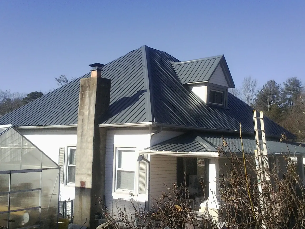Dark blue standing seam metal roof on a white farmhouse with dormer — Slate & Tile Roof Repair by Roofing Brothers in Cross Hill
