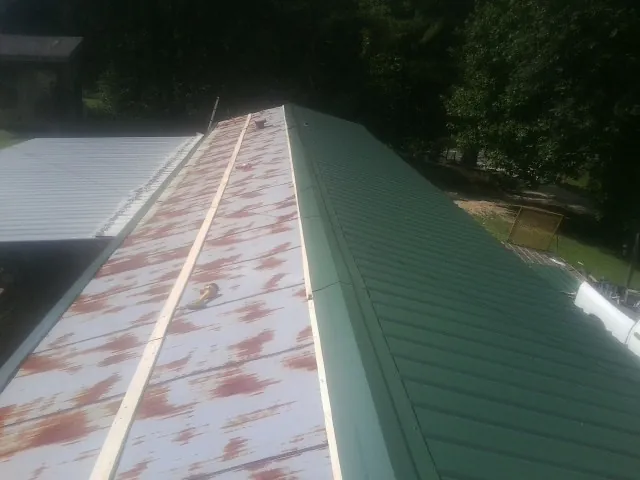 Old rusted panels beside newly installed green metal roofing — Wind Damage Roof Repair by Roofing Brothers in Cross Hill
