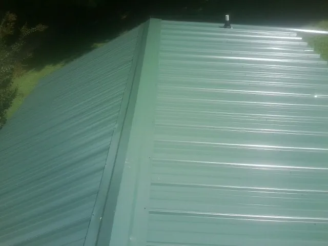 New green metal panels meeting at the ridge of a roof — Flat Roof Repair work by our crew in Cross Hill