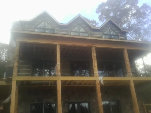 Dormers and porch framing on a large log home under construction — Roof Coating work by our crew in Cross Hill