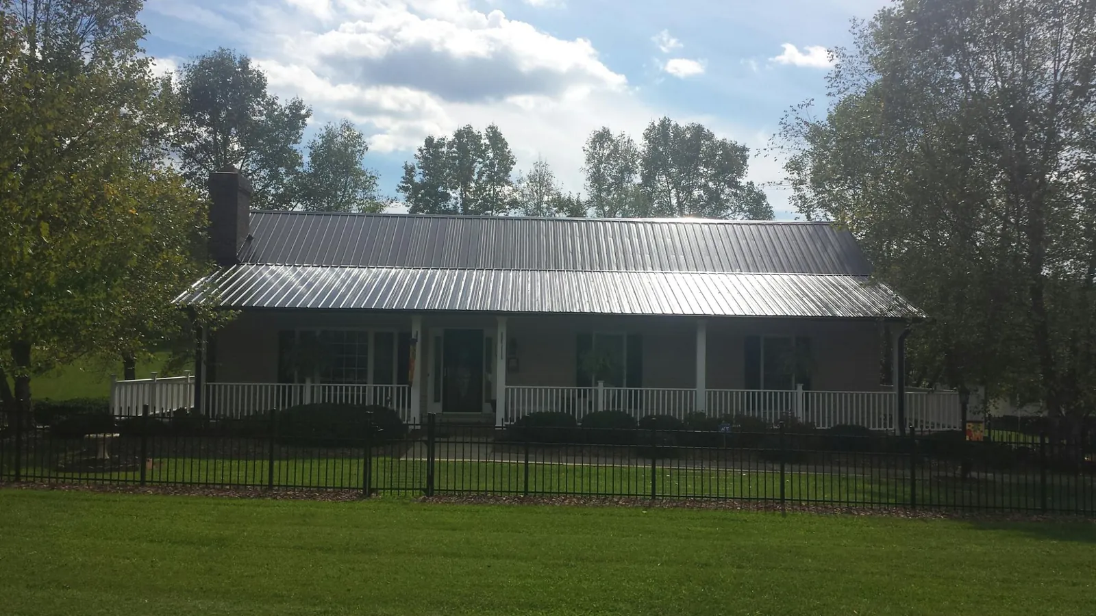 Gray metal roof on a brick ranch with a full width front porch — Gutter Guard Installation work by our crew in Cross Hill