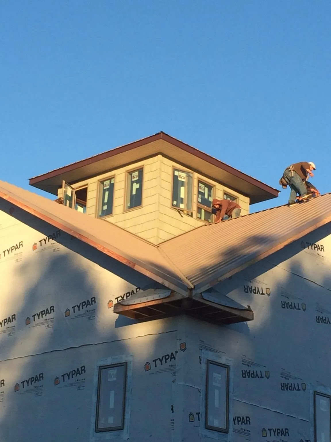 Roofers working around a rooftop cupola on a new metal roof at sunset — Roof Waterproofing in Cross Hill by Roofing Brothers